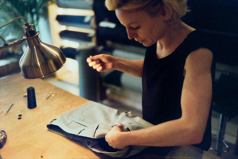 Manuela Pott arbeitet unter der Werkstattlampe an einer hellen Hose.